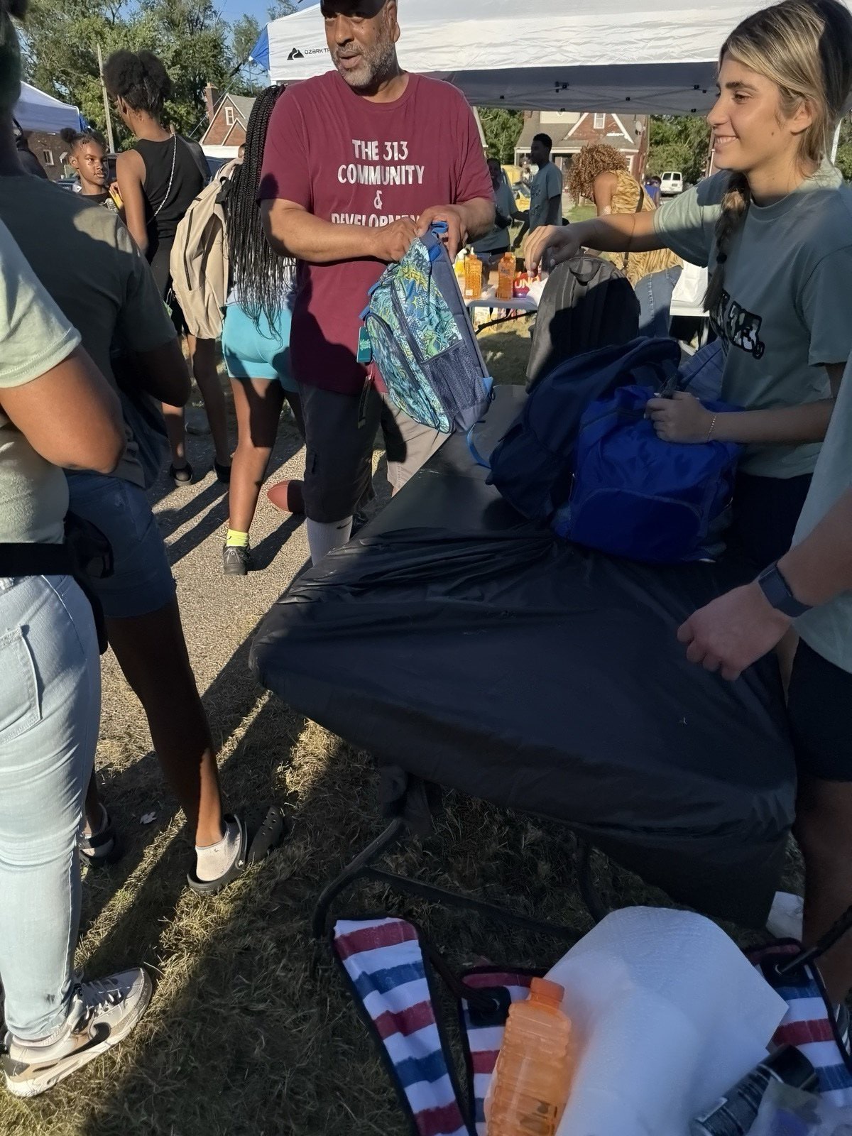 Volunteer distributing backpacks to kids